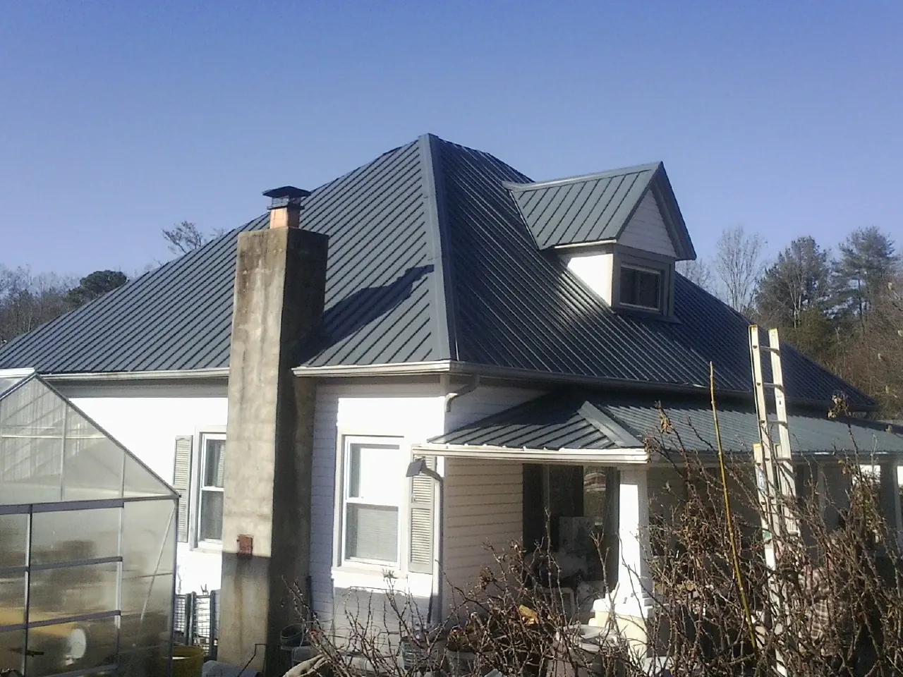 Dark blue standing seam metal roof on a white farmhouse with dormer — Slate & Tile Roof Repair by Roofing Brothers in Fabius