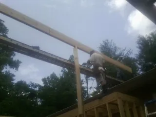 Carpenter setting a ridge beam over a new addition frame — Ice Dam Removal by Roofing Brothers in Fabius