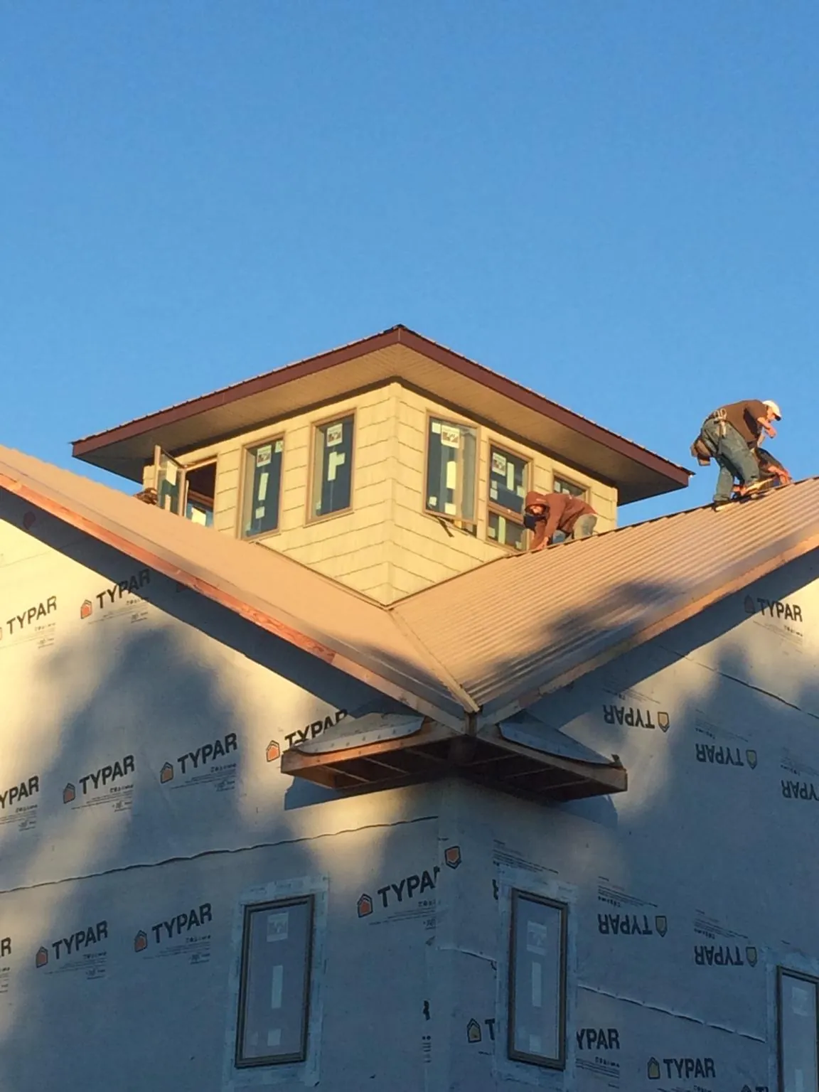 Roofers working around a rooftop cupola on a new metal roof at sunset — Roof Waterproofing in Fabius by Roofing Brothers